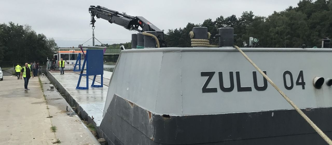 De 'Zulu 4' van Blue Line Logistics levert de blauwe metalen platen voor de test met magnetisch aanmeren af op de kade van IOK in Mol