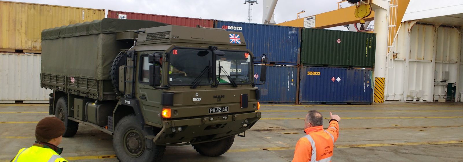 Een Antwerpse dokwerker loodst een militair voertuig van boord in operatie Defender
