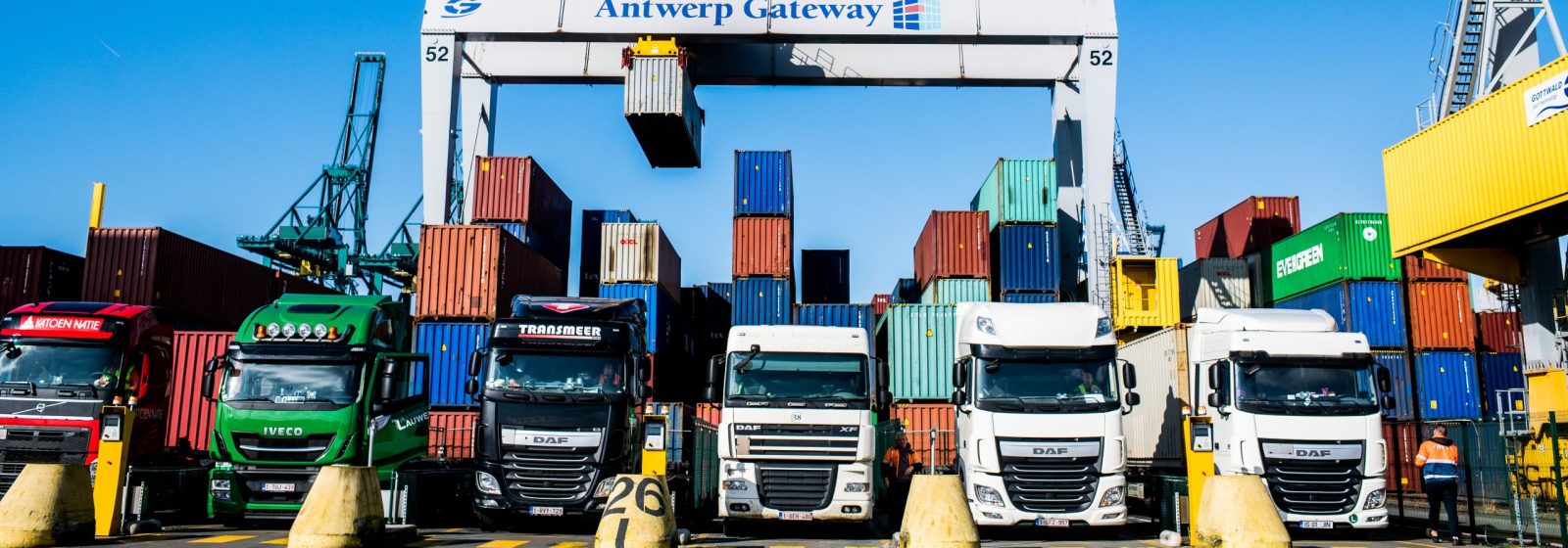 Vrachtwagens laden containers bij DP World Antwerpen.