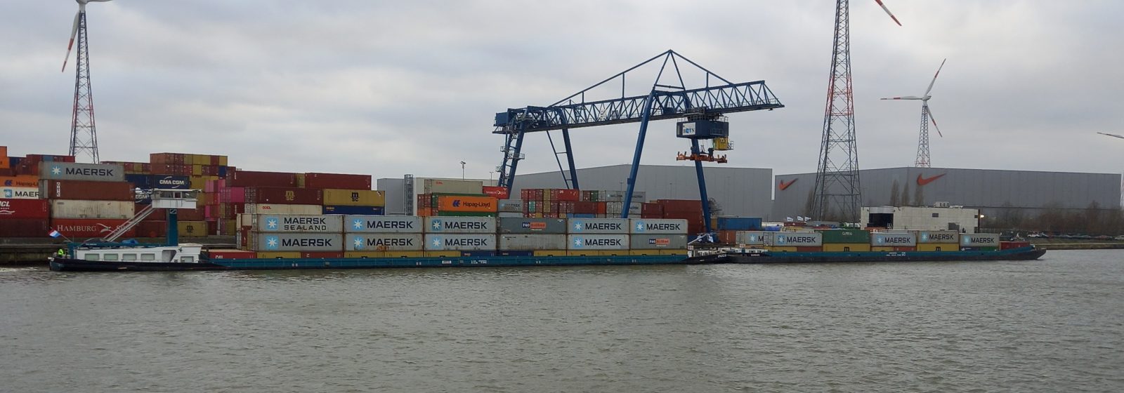 Duwkonvooi met vier lagen containers verlaat de terminal richting Antwerpen.